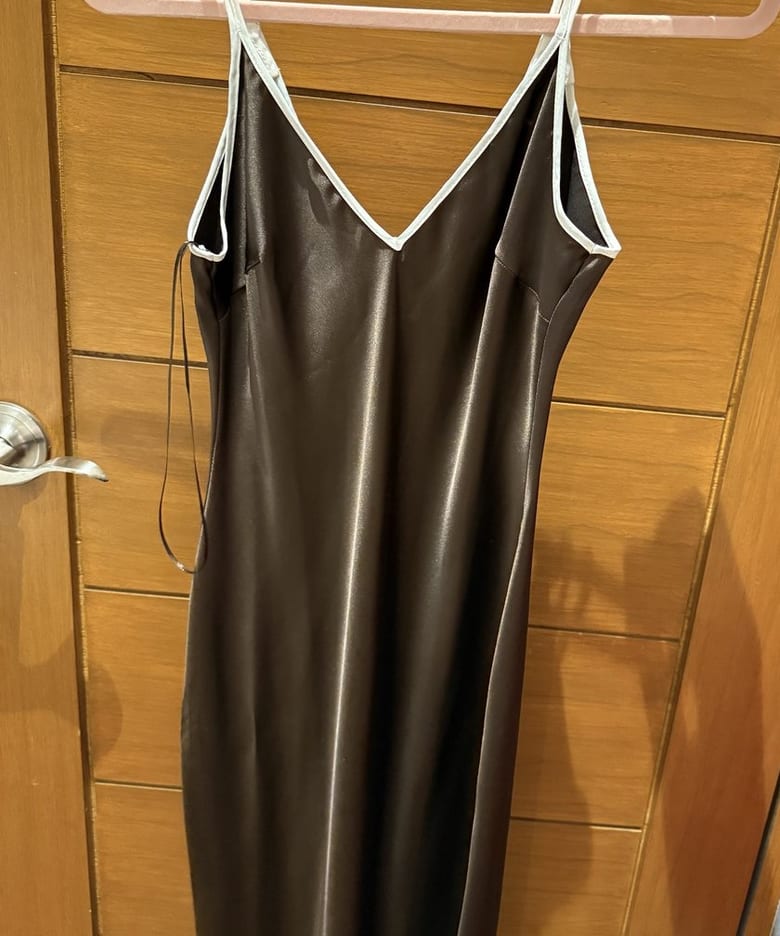 A brown satin slip dress with ivory straps on a pink hanger